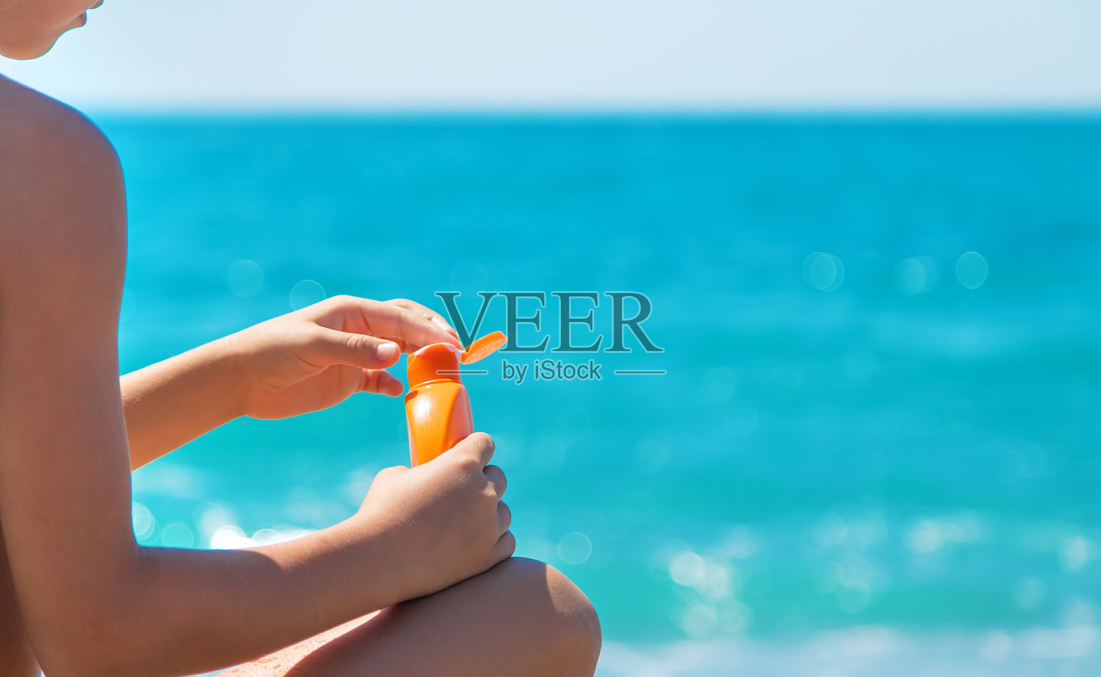 在海滩上手里拿着防晒霜。有选择性的重点。照片摄影图片