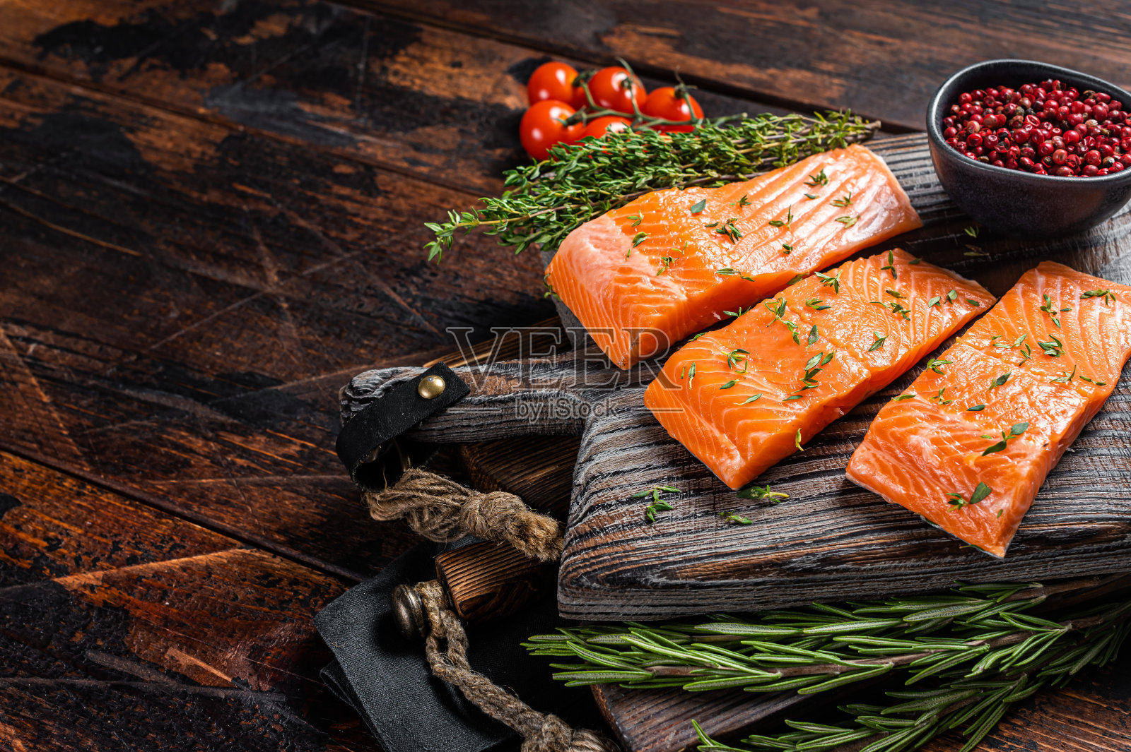 生三文鱼片配百里香和迷迭香放在木板上。木制背景。前视图。本空间照片摄影图片