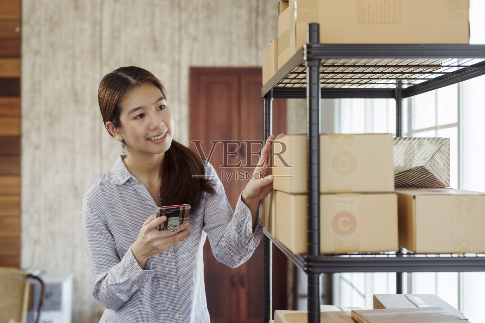 一位美丽的亚洲在线卖家在包裹盒前检查是否正确,并微笑着准备把顾客送过去。照片摄影图片