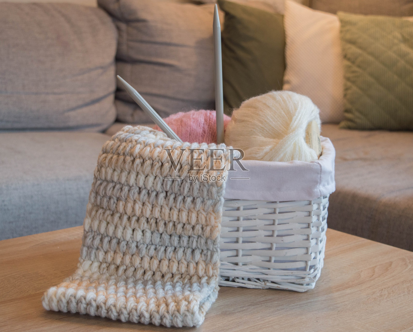 粉红色和白色的羊毛球在一个白色的篮子和编织针和针织围巾照片摄影图片