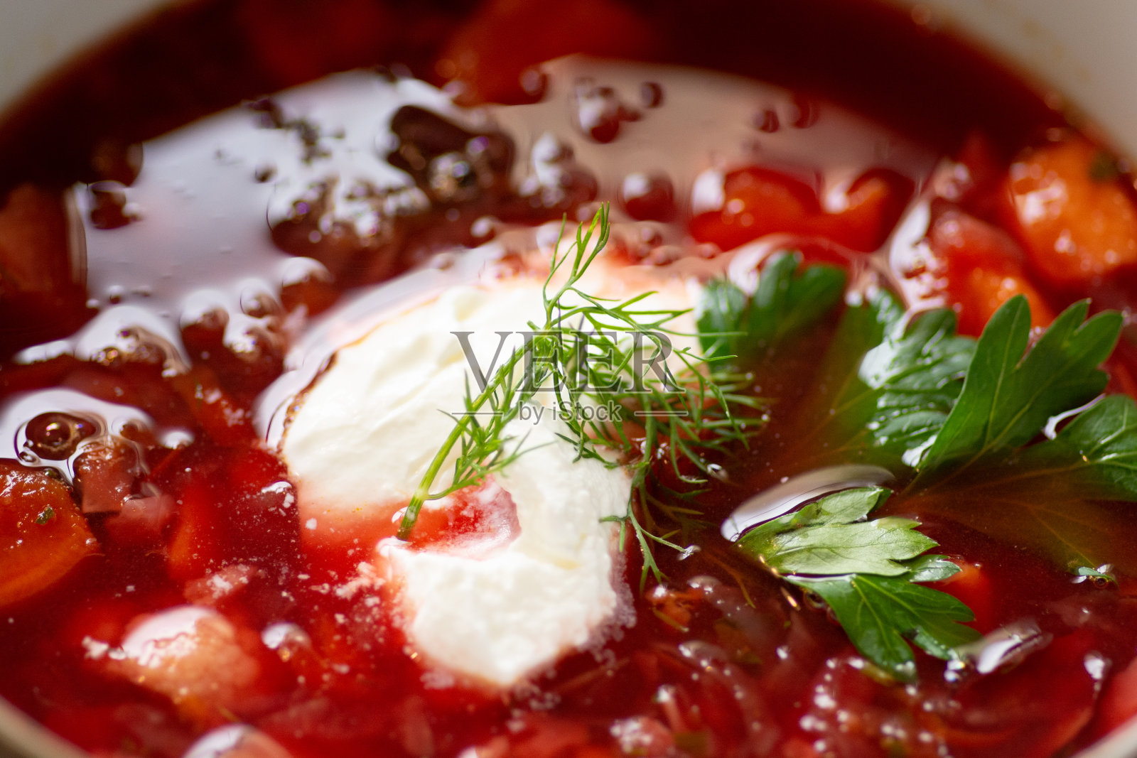 传统酸味罗宋汤的特写,乌克兰最著名的菜肴之一,以甜菜根为主要成分之一,配以酸奶油和莳萝叶照片摄影图片