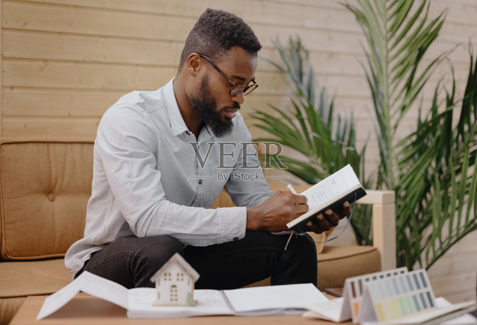 一位非裔美国男性建筑师、工程师或设计师在一个住宅建筑项目的办公室工作。一位非裔美国人手里拿着一幅微型画照片摄影图片