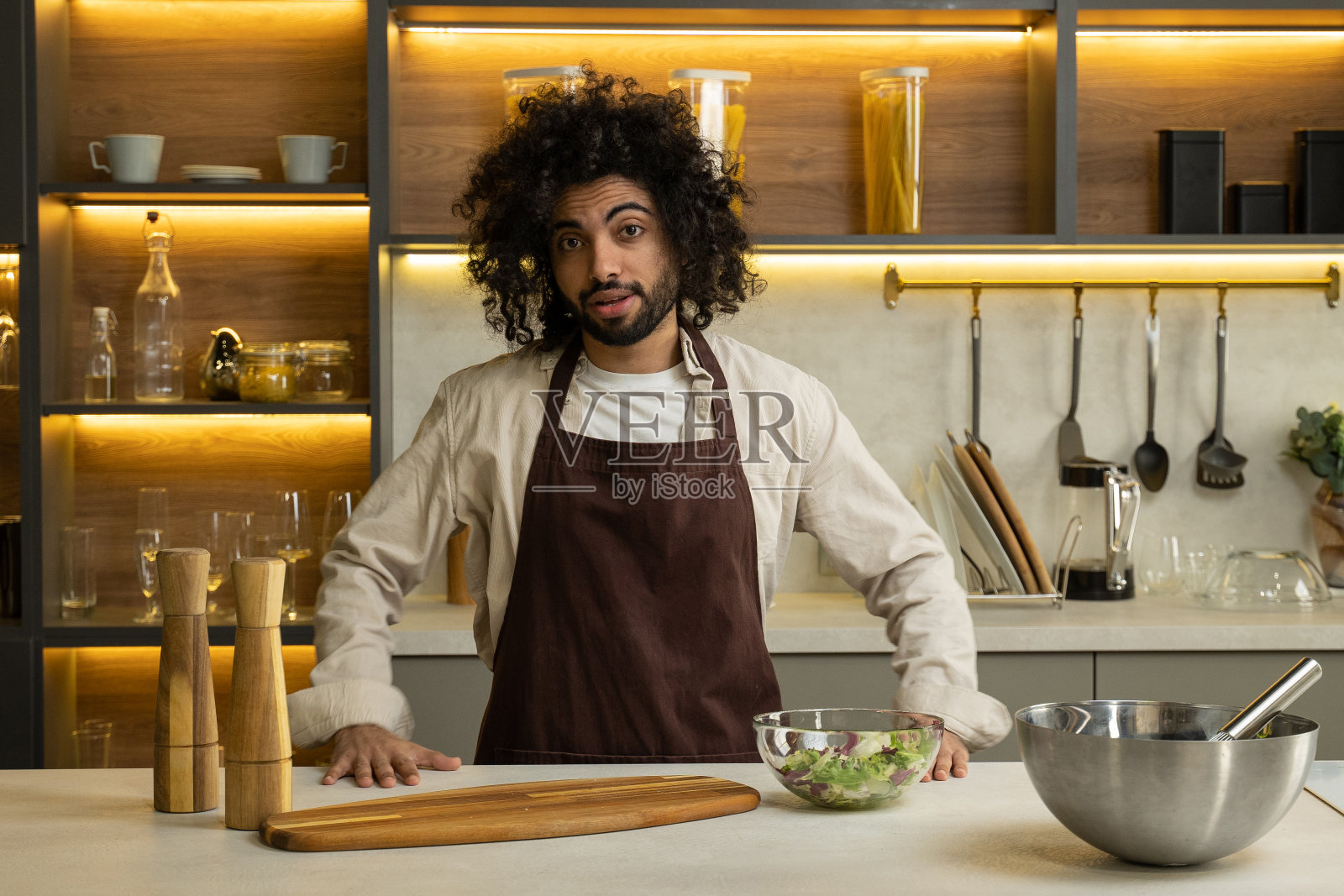 阿拉伯男子在厨房的餐桌上分享沙拉的配方照片摄影图片