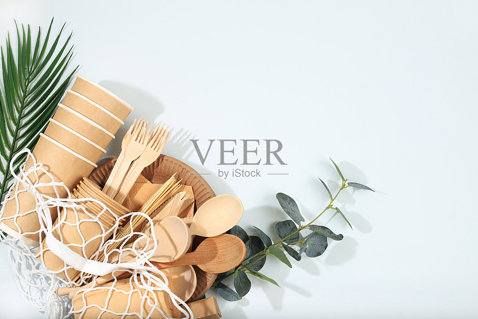 一套环保的盘子在一个生态袋在阳光明媚的桌子上。纸杯,盘子,牛皮纸餐巾,烧烤用吸管,木制叉子,勺子和刀子,模型,照片摄影图片