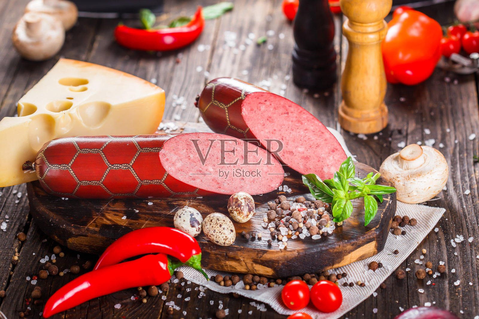 意大利腊肠配培根片,整块或切片,绿罗勒,樱桃番茄,奶酪和香料,厨房砧板,深色和忧郁,在黑色木制的孤立背景上,顶部照片摄影图片