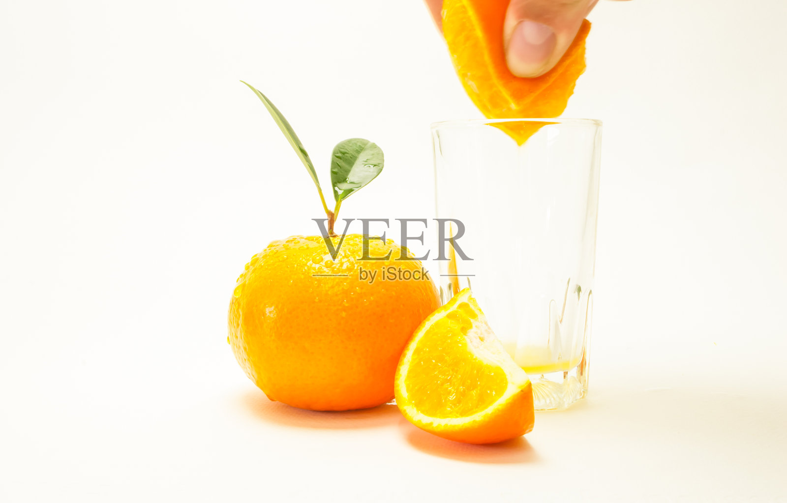 橙子被分成小块。新鲜的黄色水果在白色的背景。手拿橙子和维生素放在杯子里,注意特定的点。概念与健康,文字空间照片摄影图片