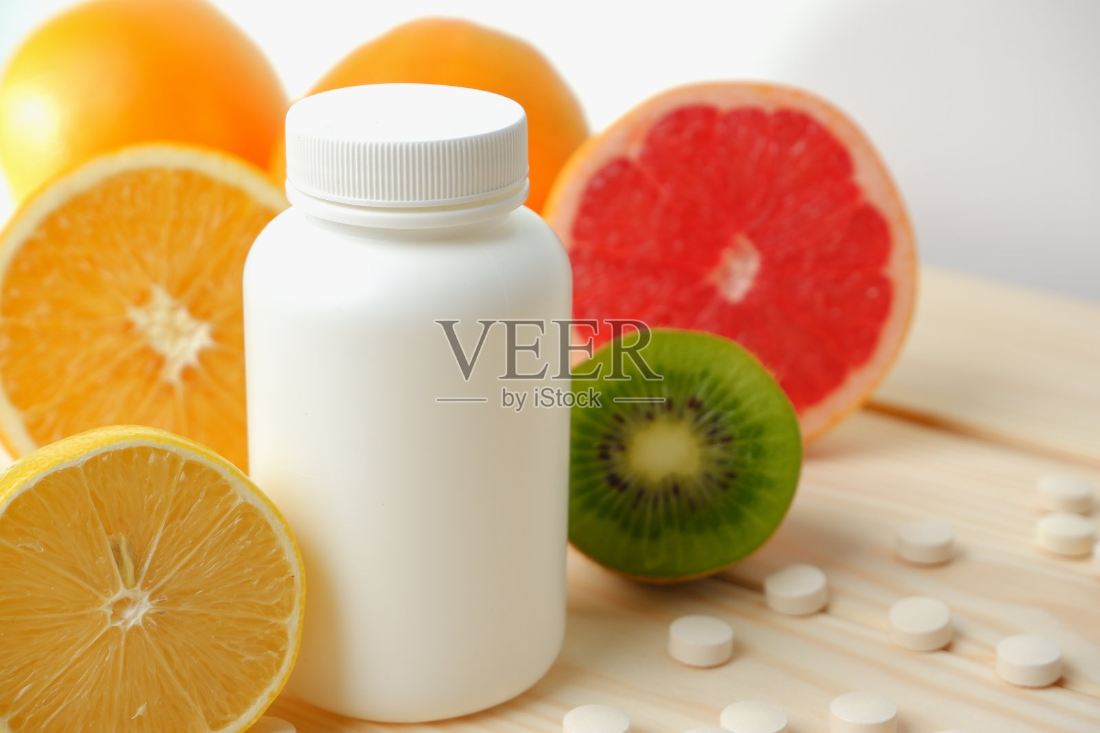维生素。医学概念。药房或自然。白色的瓶子里装着维他命,散落的药丸。多汁的成熟柑橘水果片。柠檬。橙色。葡萄柚。照片摄影图片