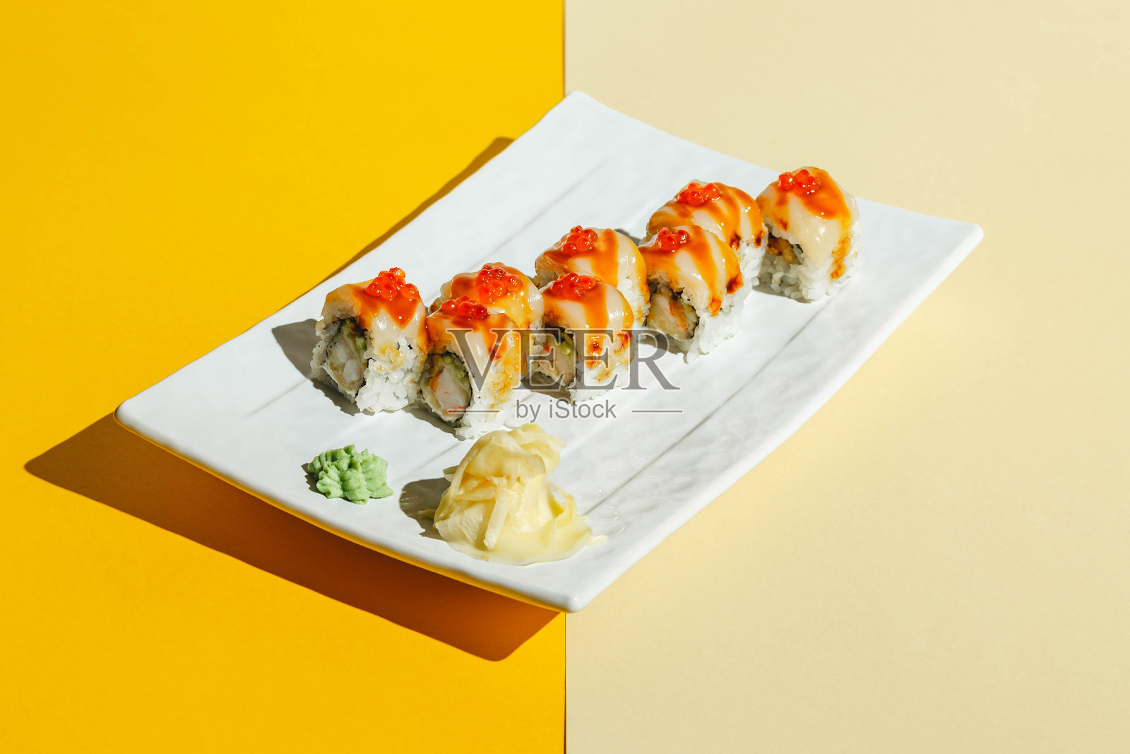 寿司卷配鳗鱼、虾、黄瓜、奶油芝士,点缀红鱼子酱。坚硬的光,深深的阴影照片摄影图片