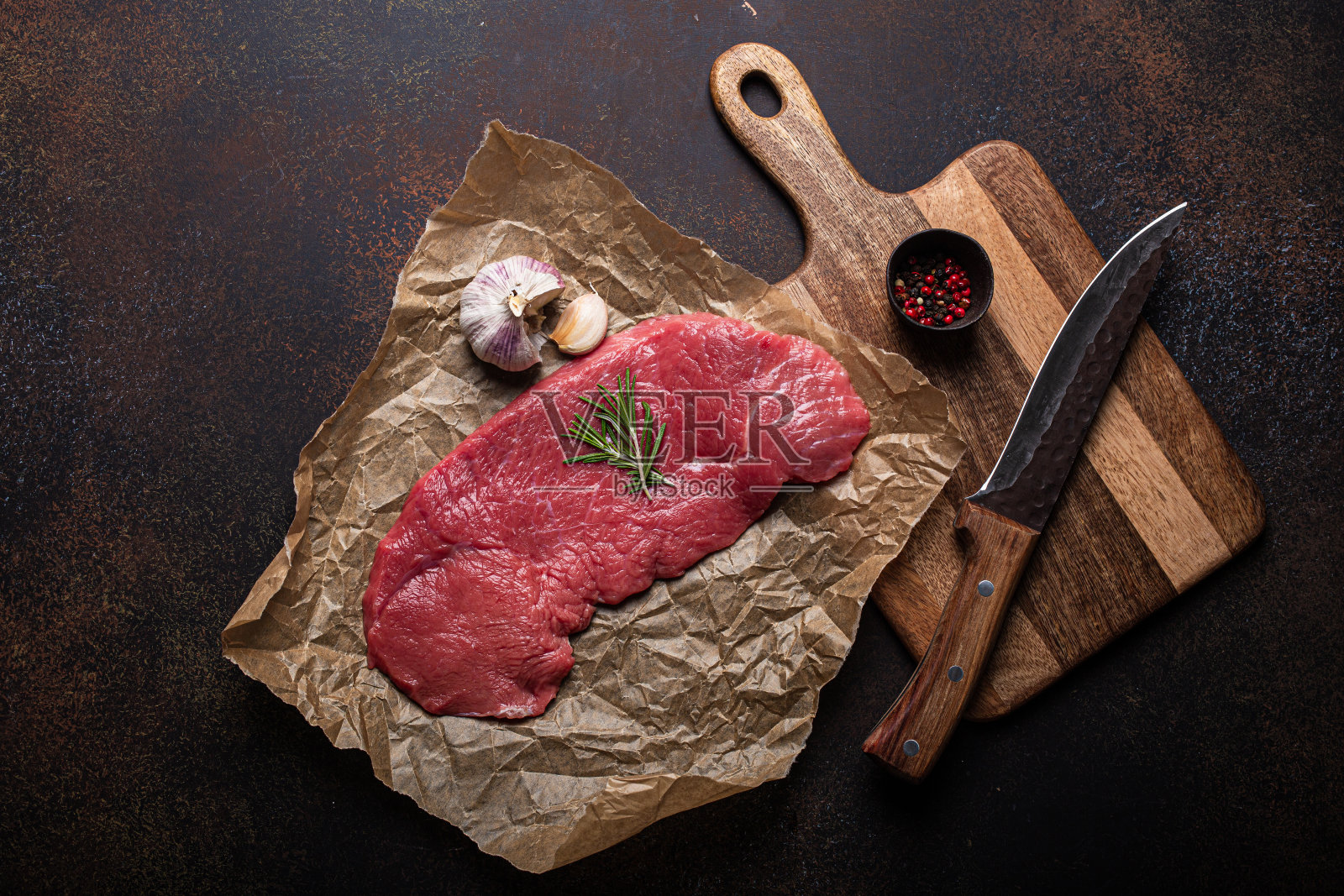 烤纸上放牛扒,配以迷迭香、大蒜和香料照片摄影图片