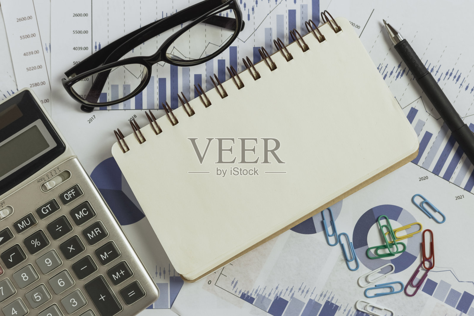 财务经营理念,桌上空空如也的笔记本,还有笔和计算器。文书工作,财务投资,图表营销在桌子上工作。照片摄影图片