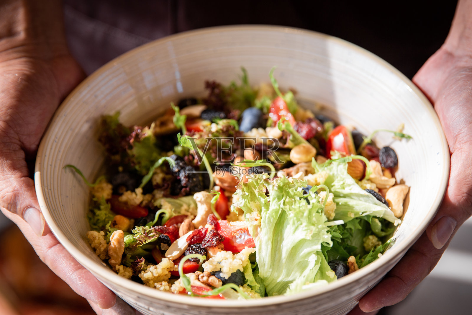 一个年轻的亚洲人手里拿着一盘什锦沙拉。健康的生活方式。照片摄影图片