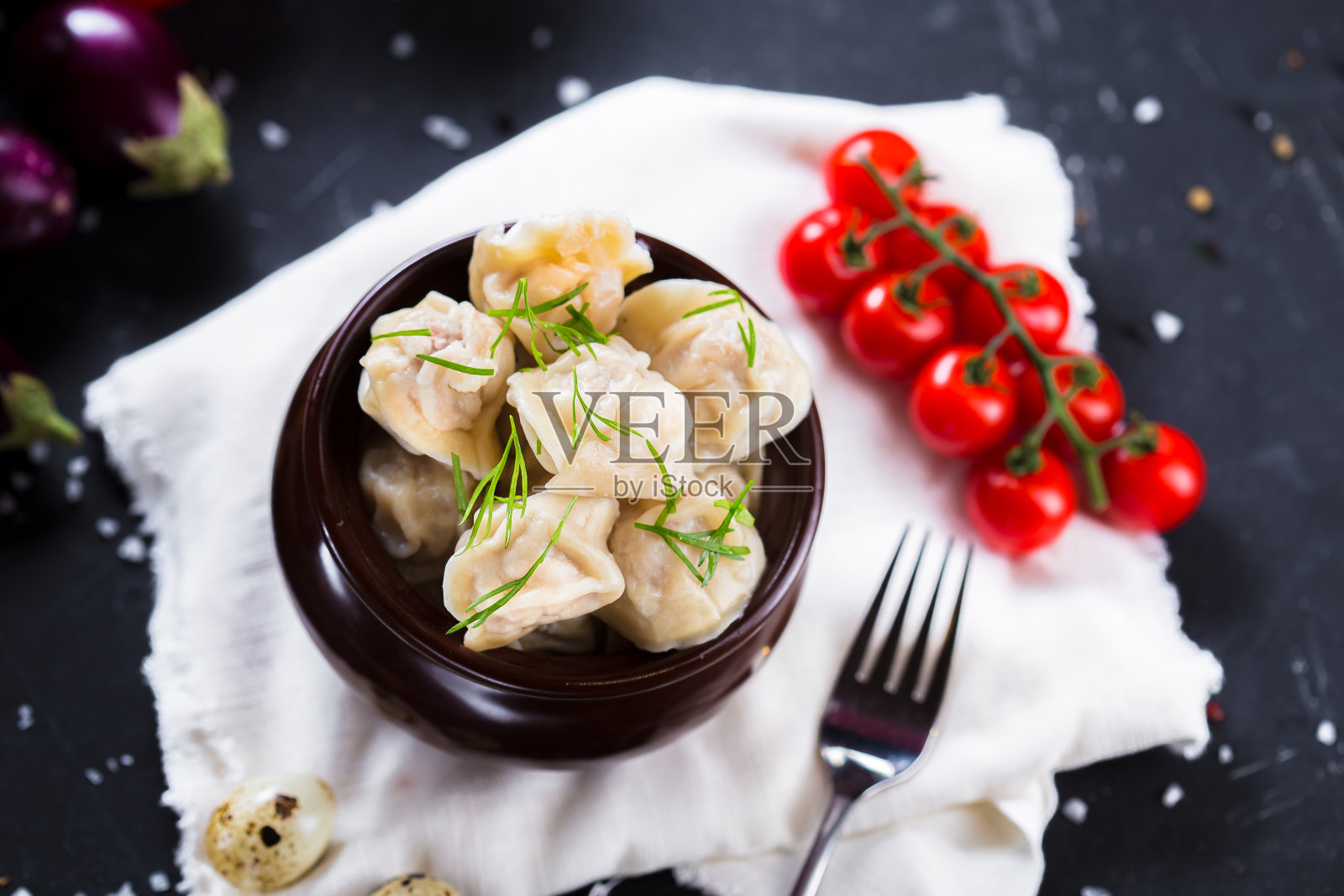 盘子上放着香草饺子,圣女果,黑色孤立背景的餐具,特写,顶部照片摄影图片