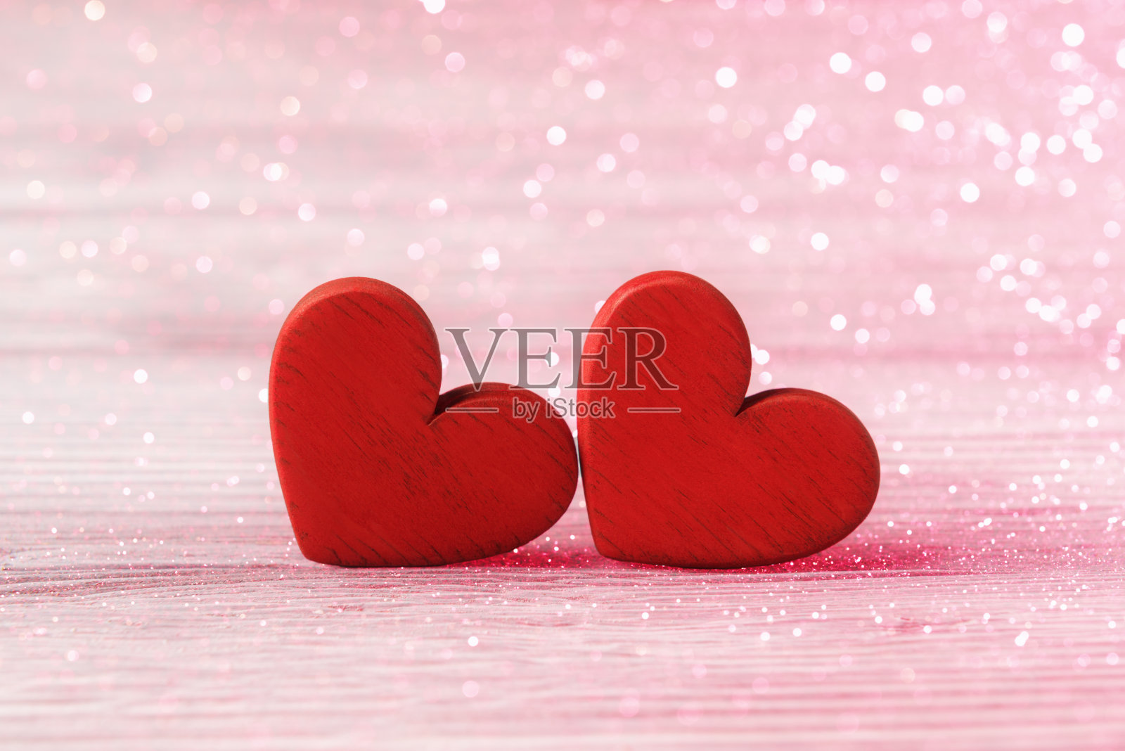 两颗红色的情人节爱心放在散焦的节日彩灯上。Valentinea节的问候照片摄影图片