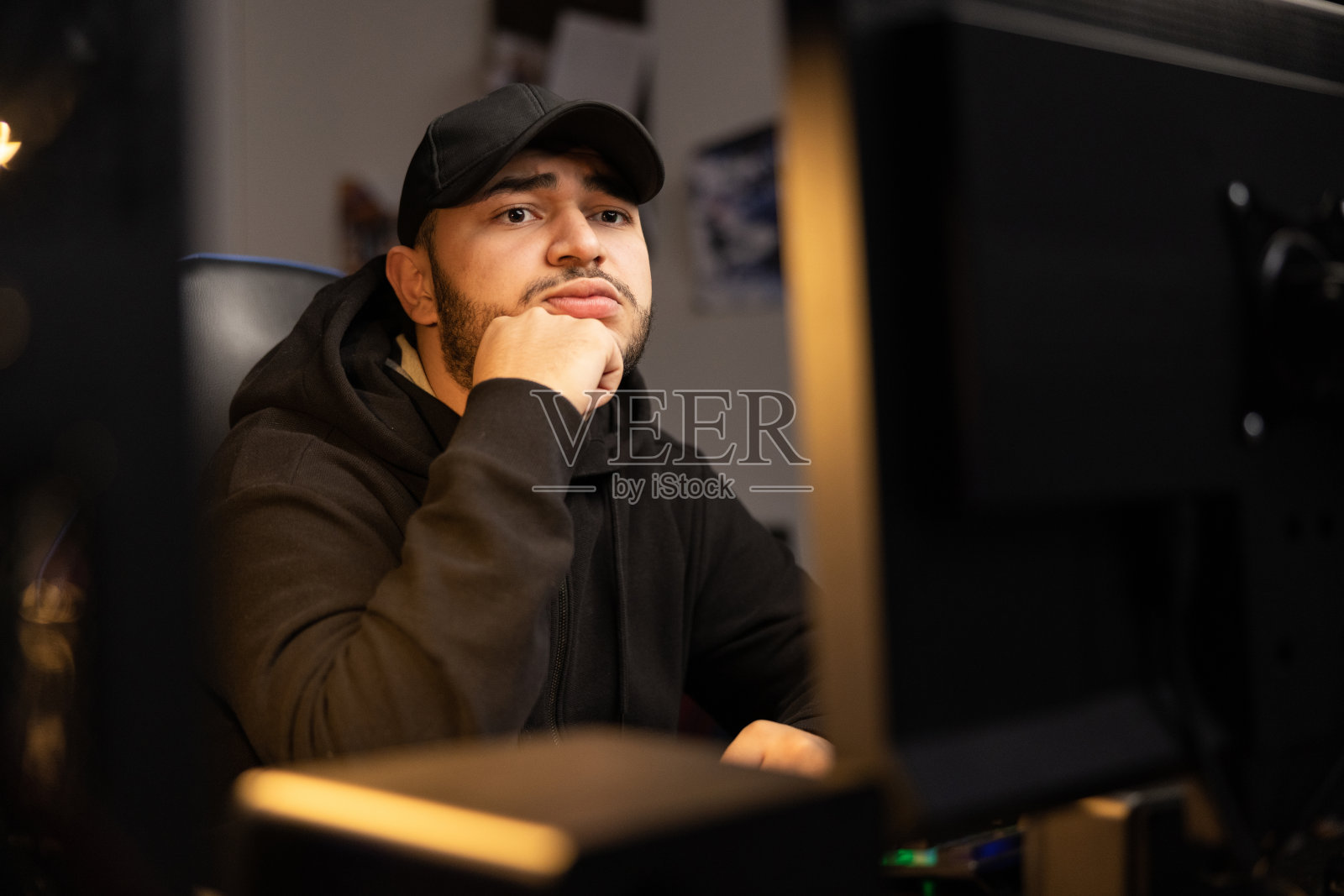 这是一个留着胡子、穿着黑色衣服、带帽运动衫的男人的肖像,他在IT行业远程工作,他是程序员、计算机科学家、数据库开发人员照片摄影图片