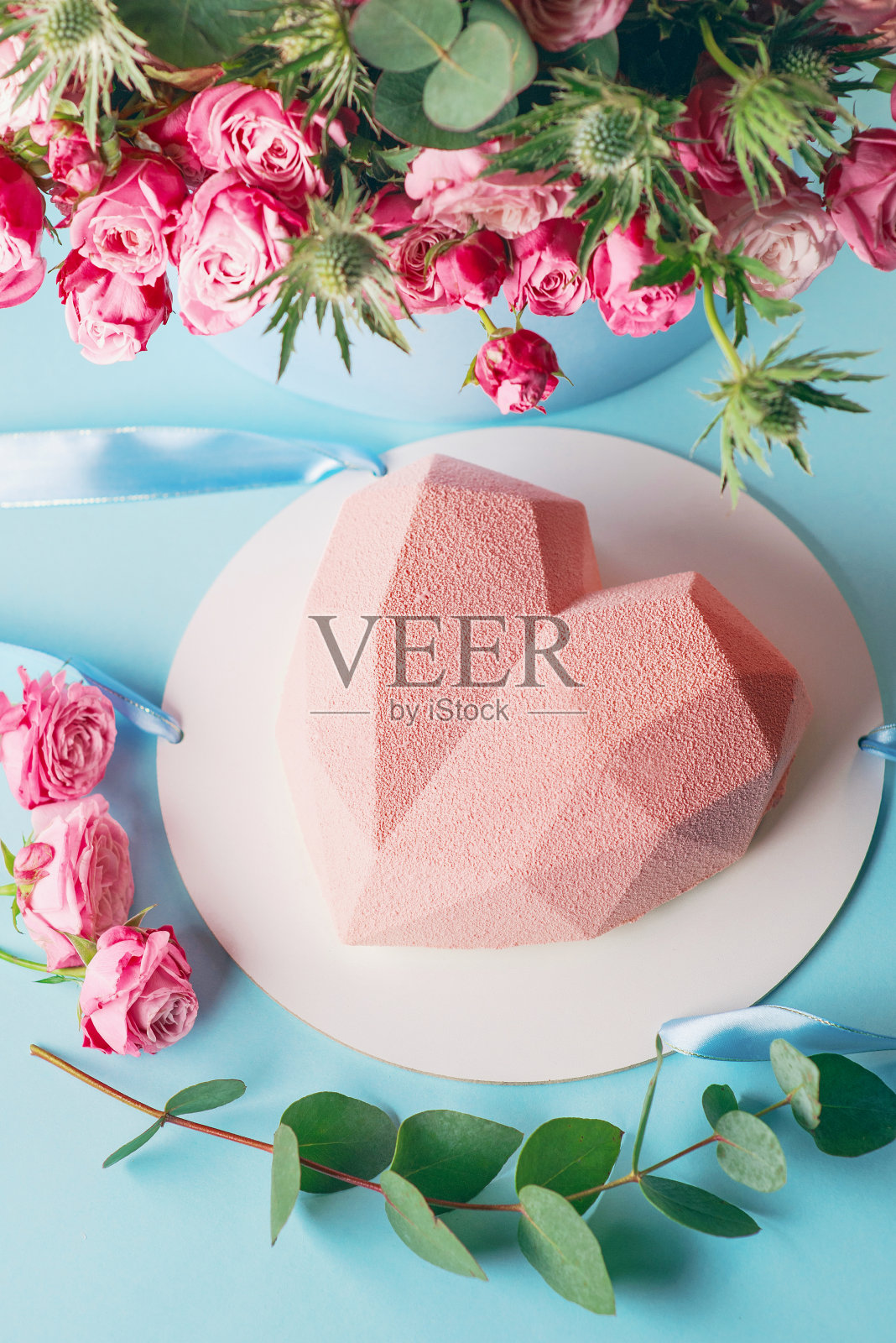 时尚的现代设计粉红色心形蛋糕在蓝色的背景与玫瑰照片摄影图片