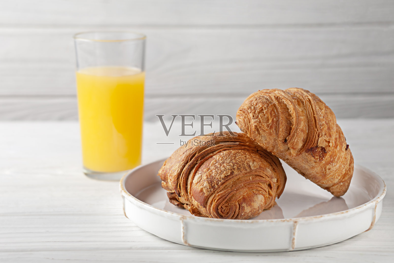 新鲜出炉的牛角面包配鲜榨橙汁。欧洲早餐。照片摄影图片