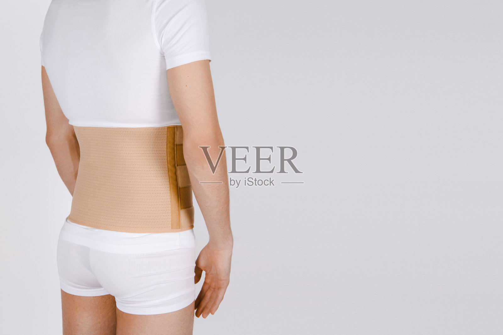 人体上的骨科腰椎紧身衣。背部支撑,腰部支撑带用于背部。背部锁骨脊椎矫正器。术后疝气手术后孕妇和产后腰支具照片摄影图片