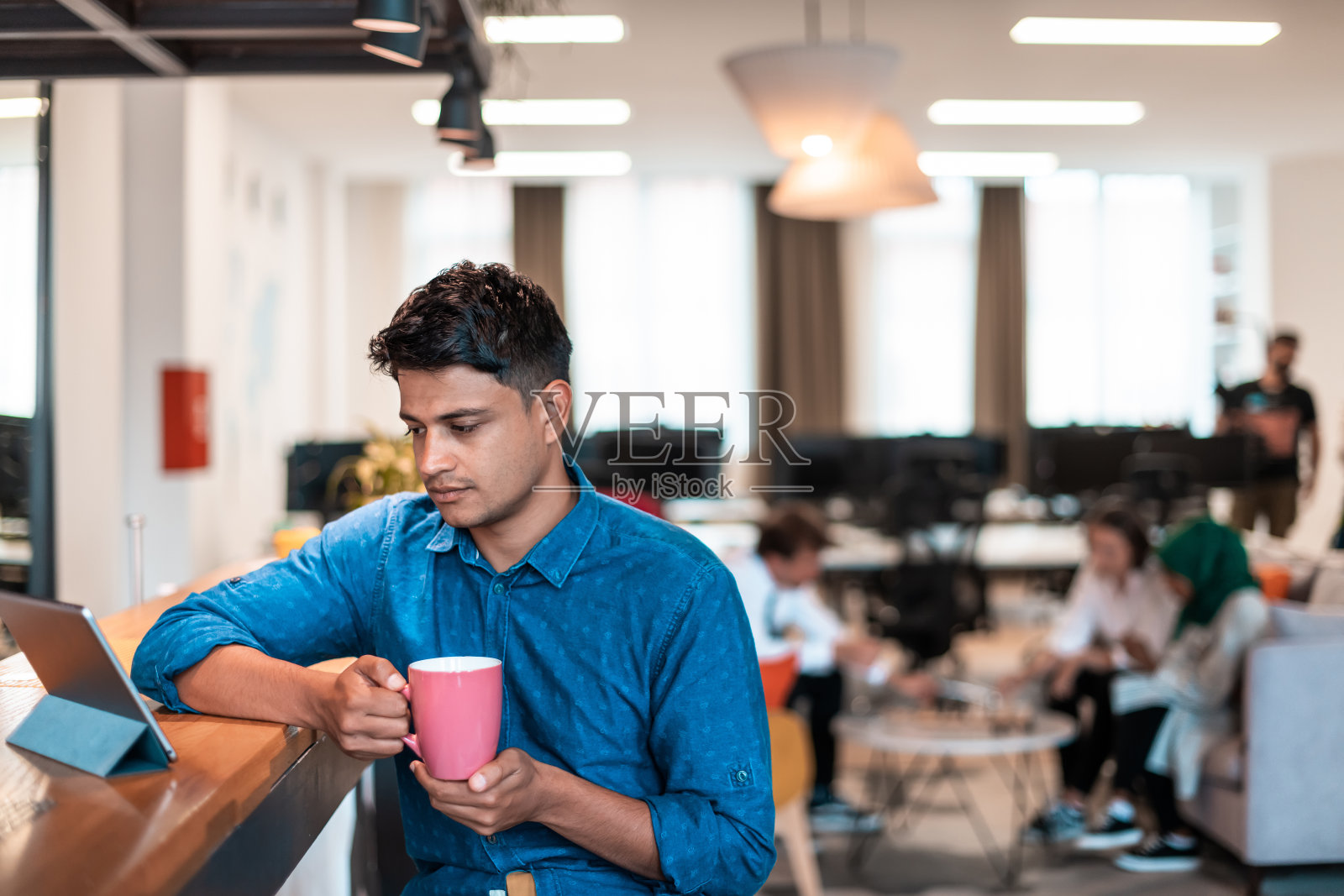 休闲商务人士在现代开放式启动办公室休闲区使用笔记本电脑喝茶休息照片摄影图片