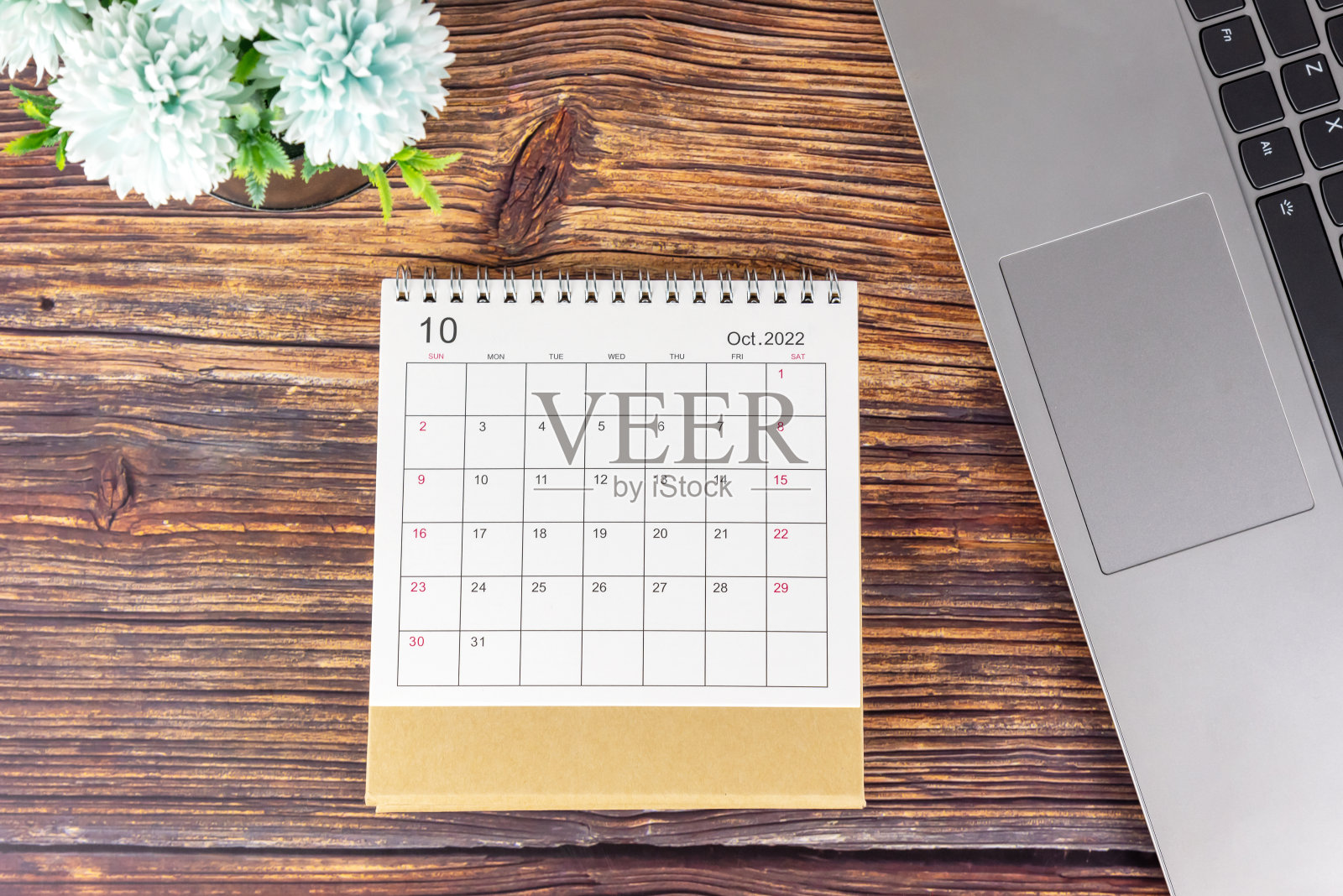 2022年10月日历日期笔记本电脑和蓝色的花在黑色的花瓶在质朴的木桌上。照片摄影图片