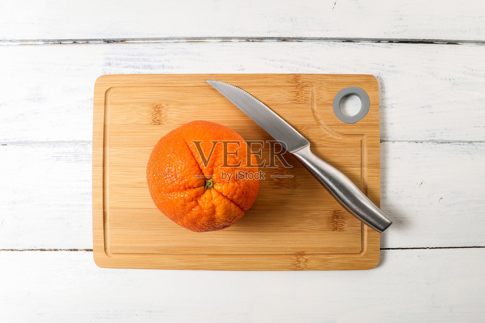 竹制菜板上的大橘子和刀照片摄影图片