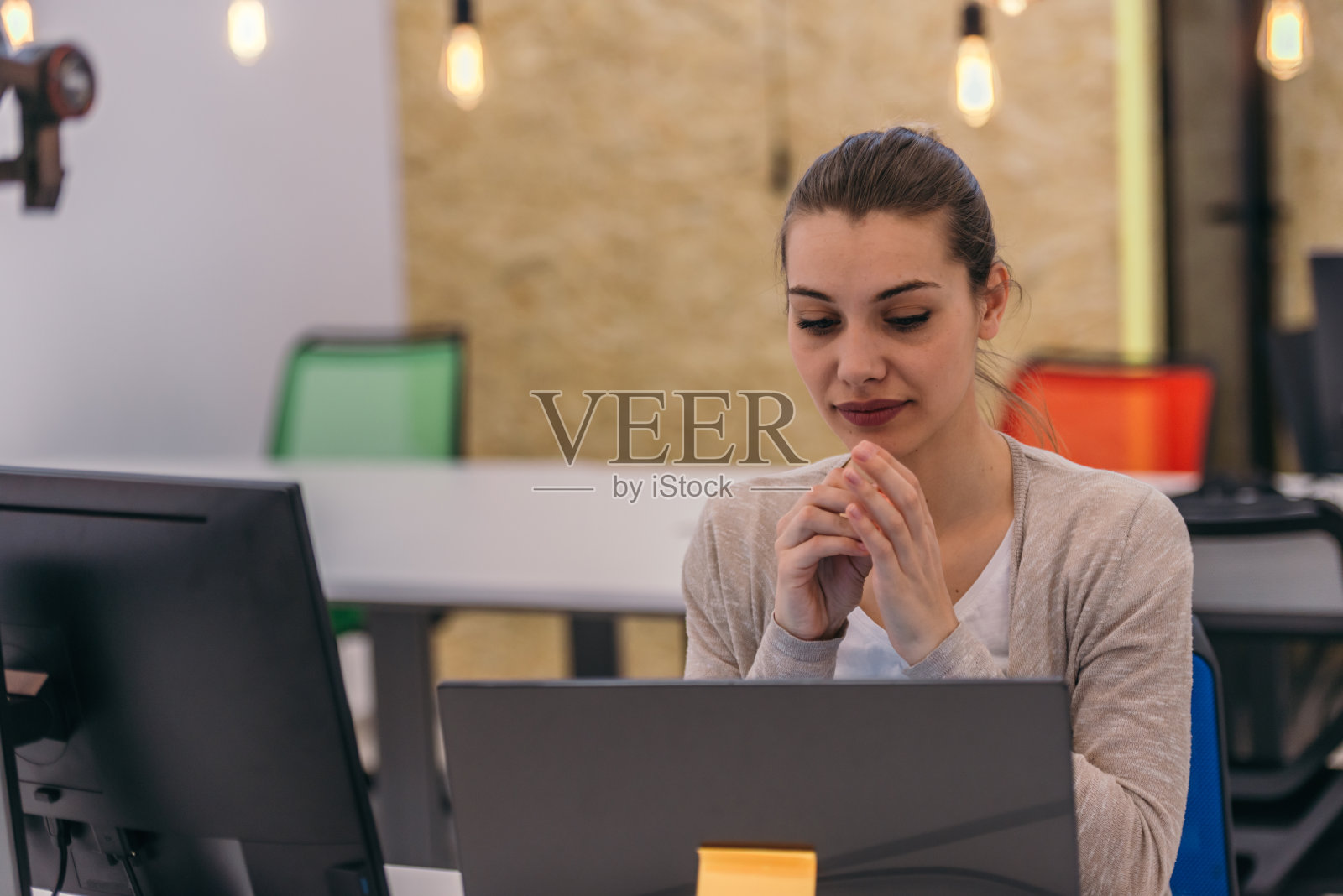 一个有吸引力的女商人在电脑上工作,并与她的同事在办公室交谈。照片摄影图片