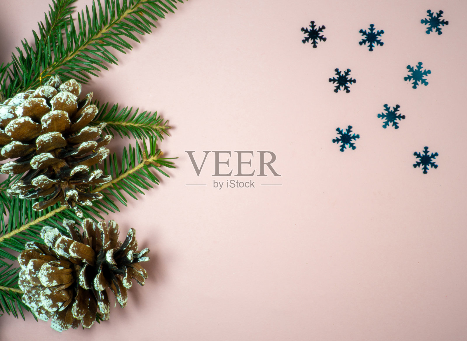 树枝上的冷杉球果和雪花。新年贺卡。粉红色背景的圣诞贺卡。照片摄影图片
