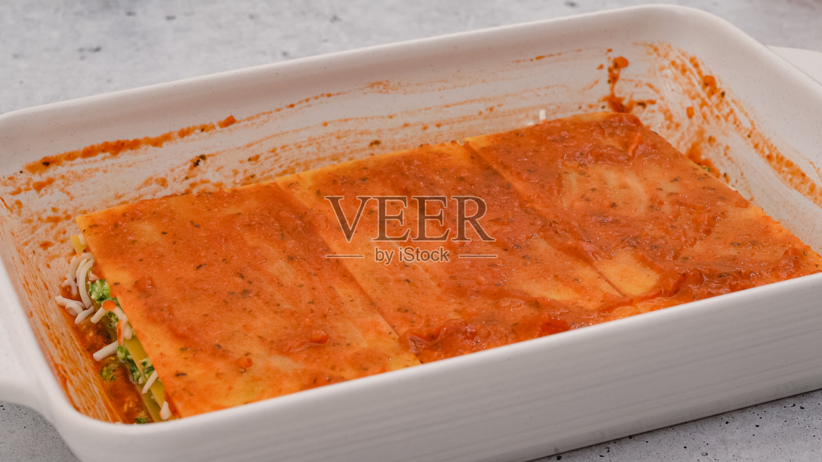 组装烤宽面条。最后一层烤宽面条上浇上番茄酱。菠菜千层面分步食谱照片摄影图片