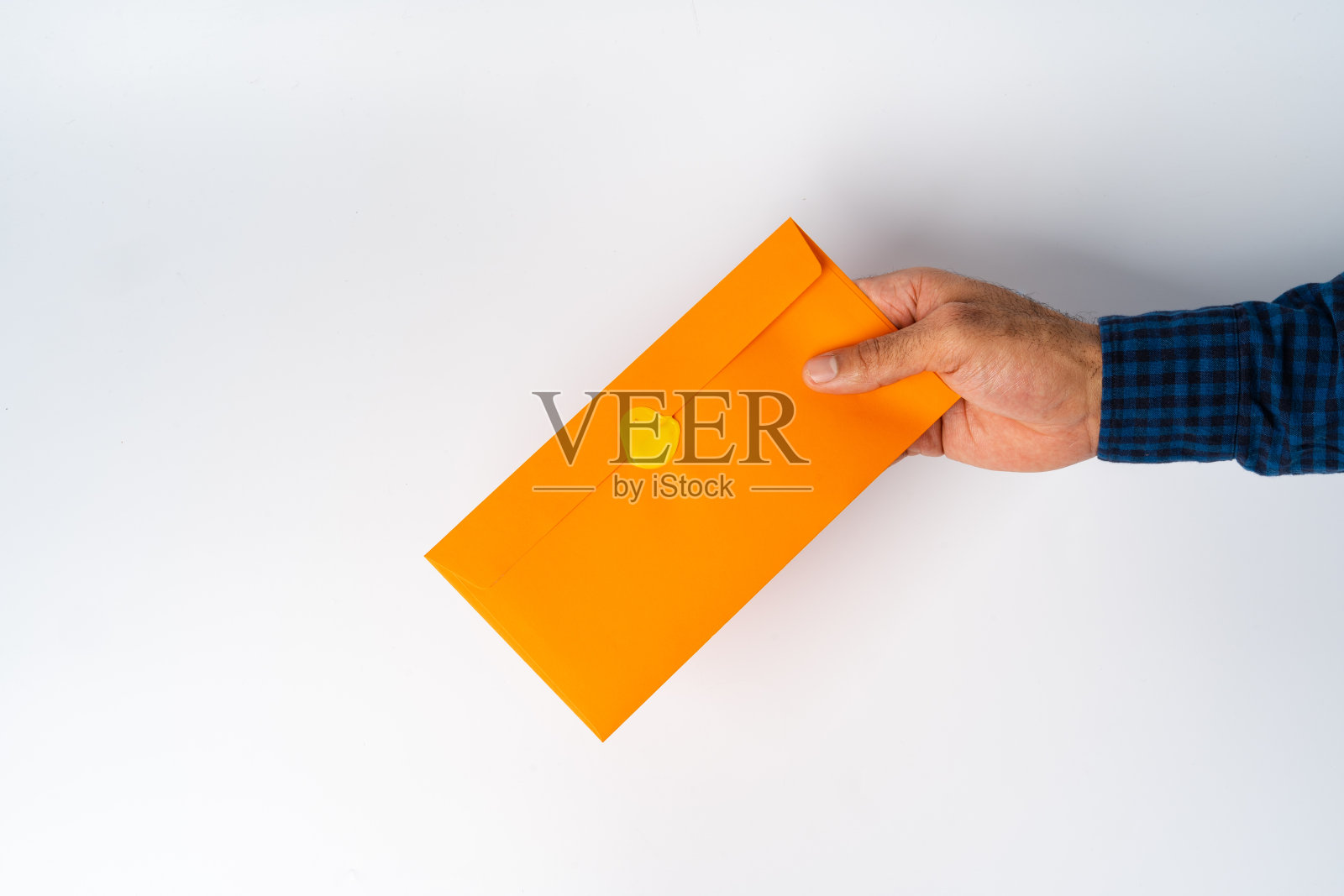 男性的手在白色表面上拿着封闭的信封照片摄影图片