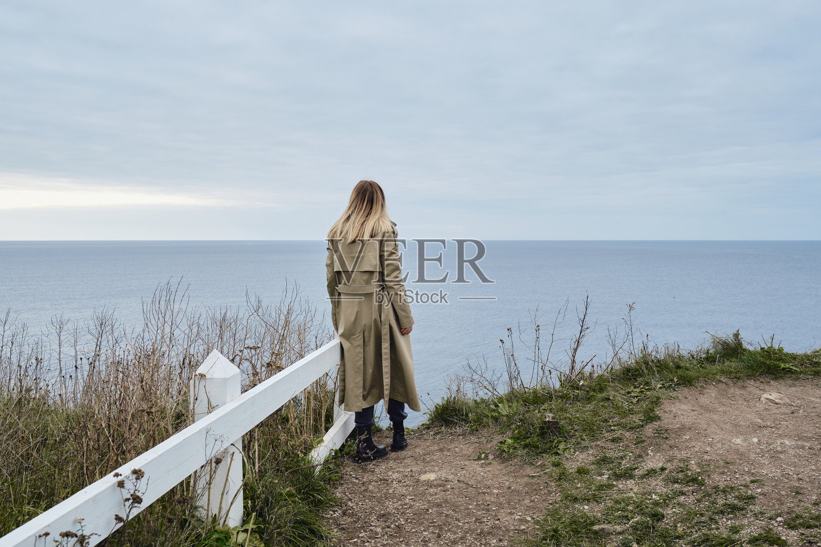 女孩站在悬崖边,看着大海。女人望向远方。令人惊叹的自然风景。美丽的岩石和大海。和谐、轻松的生活方式。旅行,冒险照片摄影图片