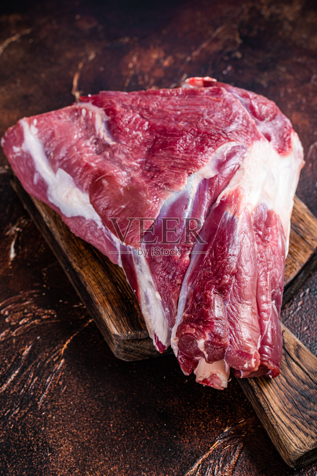 肉铺上生羊肉大腿。黑暗的背景。俯视图照片摄影图片