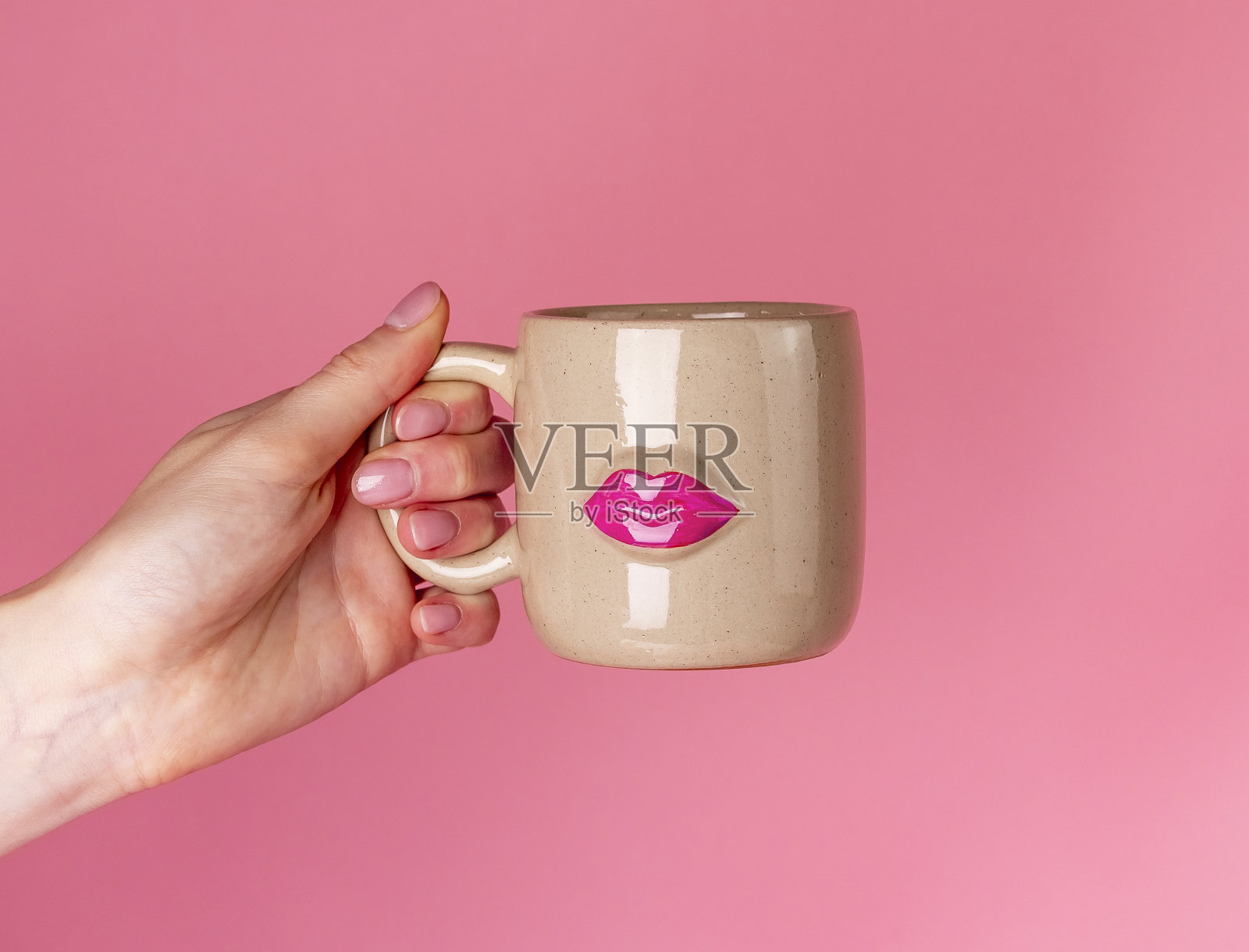 情人节的概念。手握杯子与嘴唇图像在粉红色的背景。情人节送给女人的礼物照片摄影图片