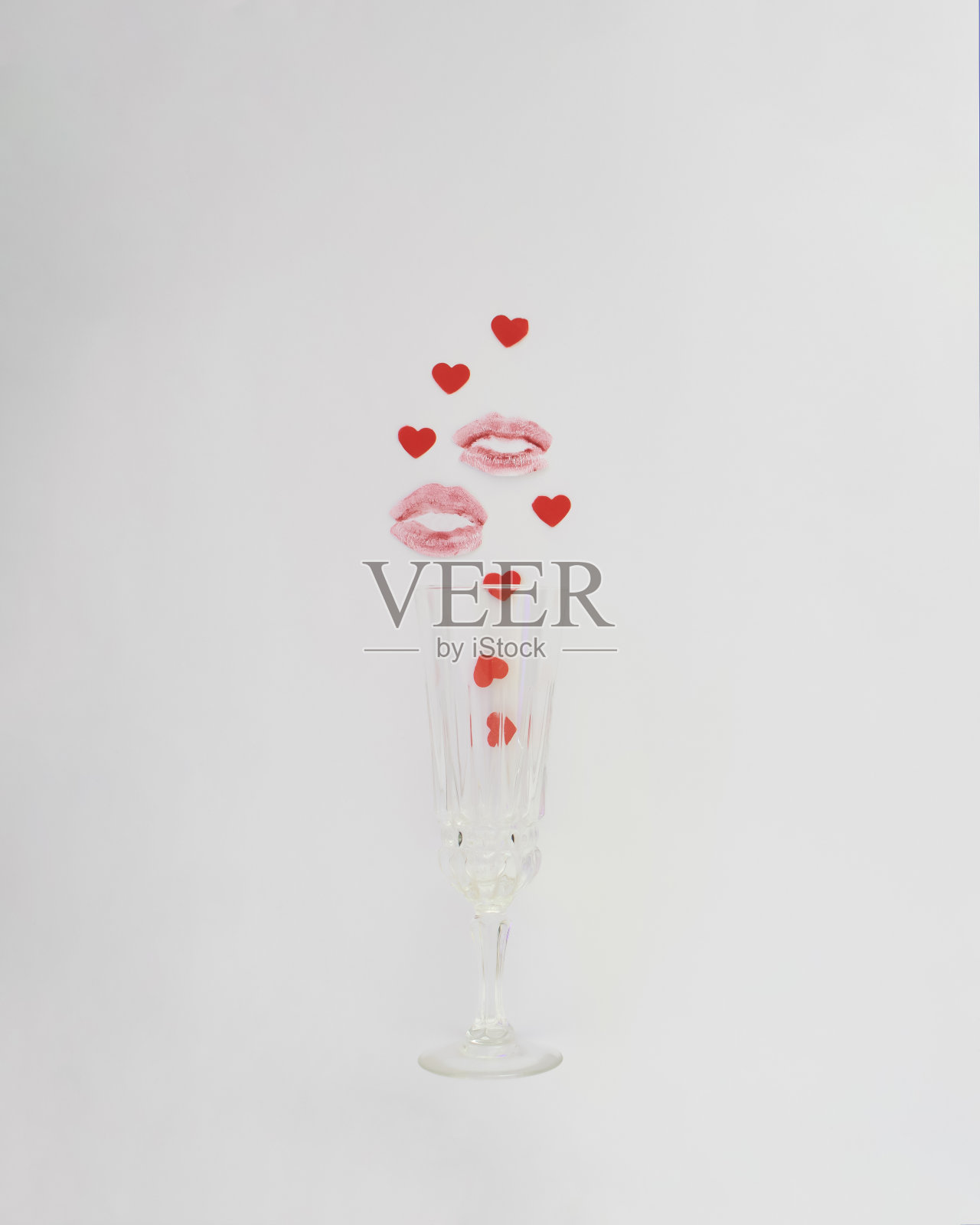 白色背景上,从酒杯中冒出红色小爱心的亲吻。情人节创意概念,爱意口红设计照片摄影图片
