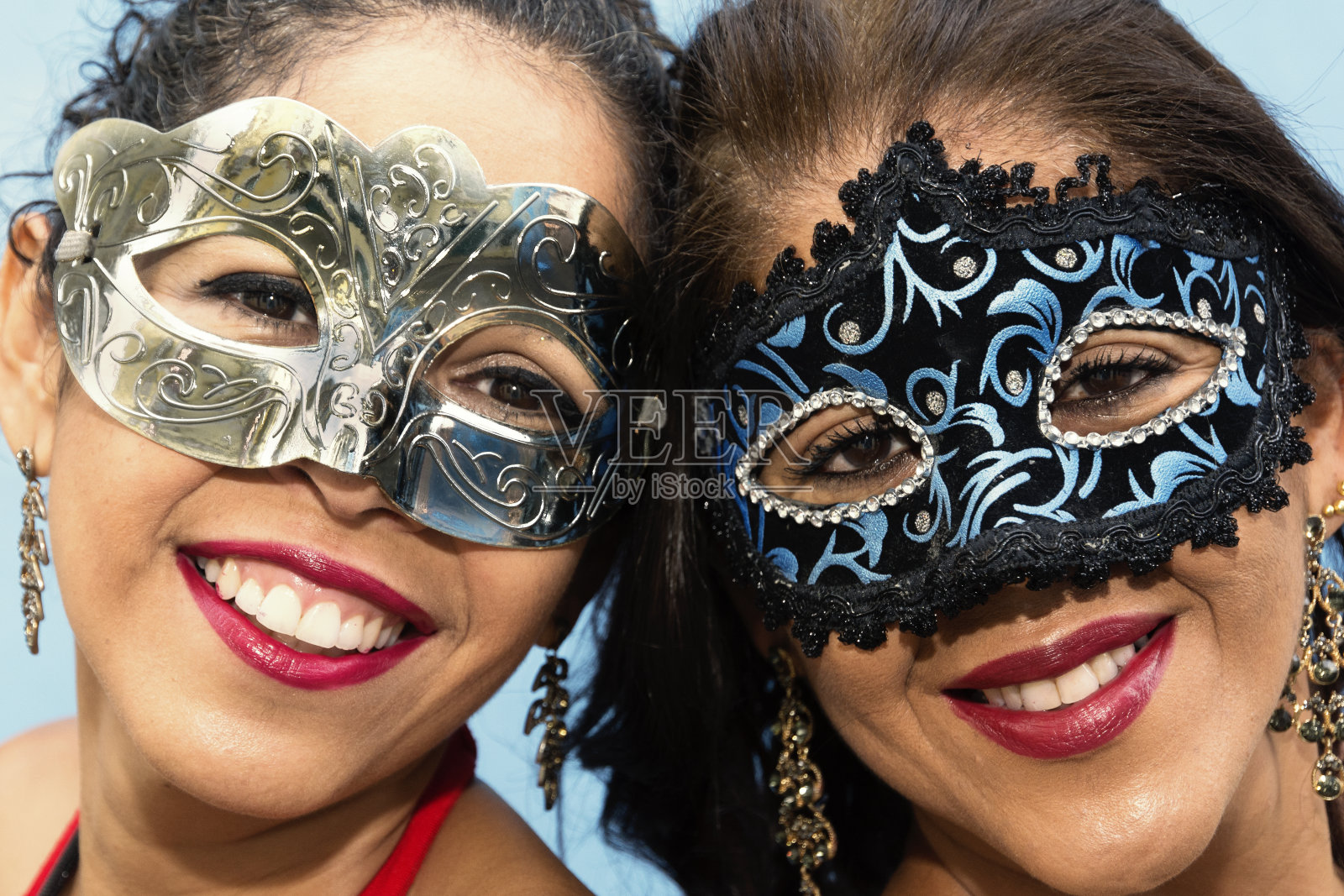 在灯光背景下,两个戴着威尼斯狂欢节面具的女人的脸部特写。照片摄影图片