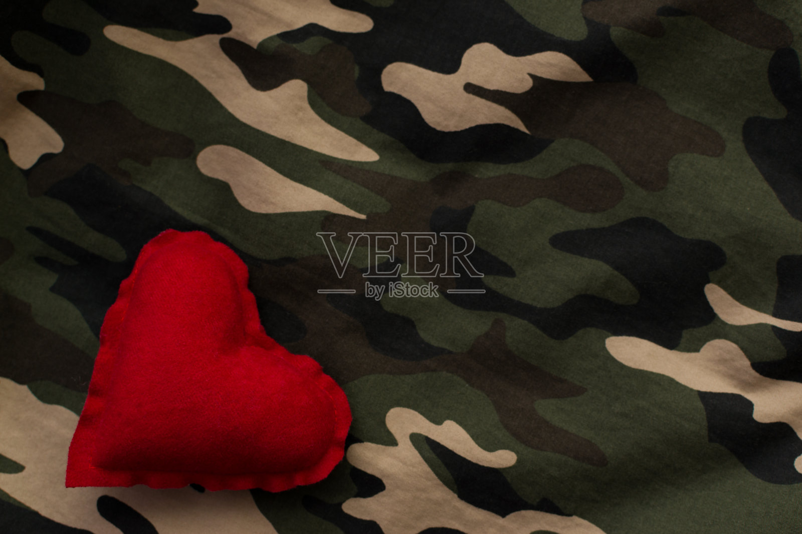 红心军用迷彩服上有拷贝空间。爱情与战争观念照片摄影图片