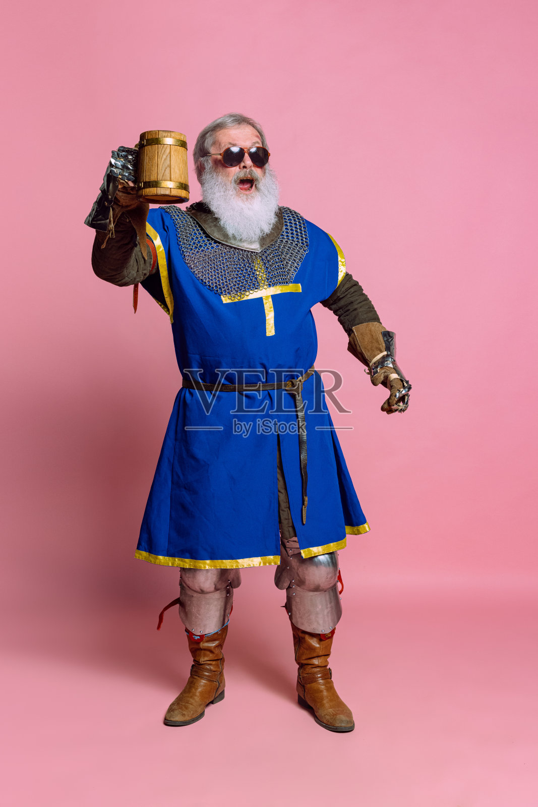 灰色胡子老人的肖像,勇敢的中世纪武士或骑士,穿着盔甲,剑孤立在粉红色的背景上。比较时代、历史、节日照片摄影图片