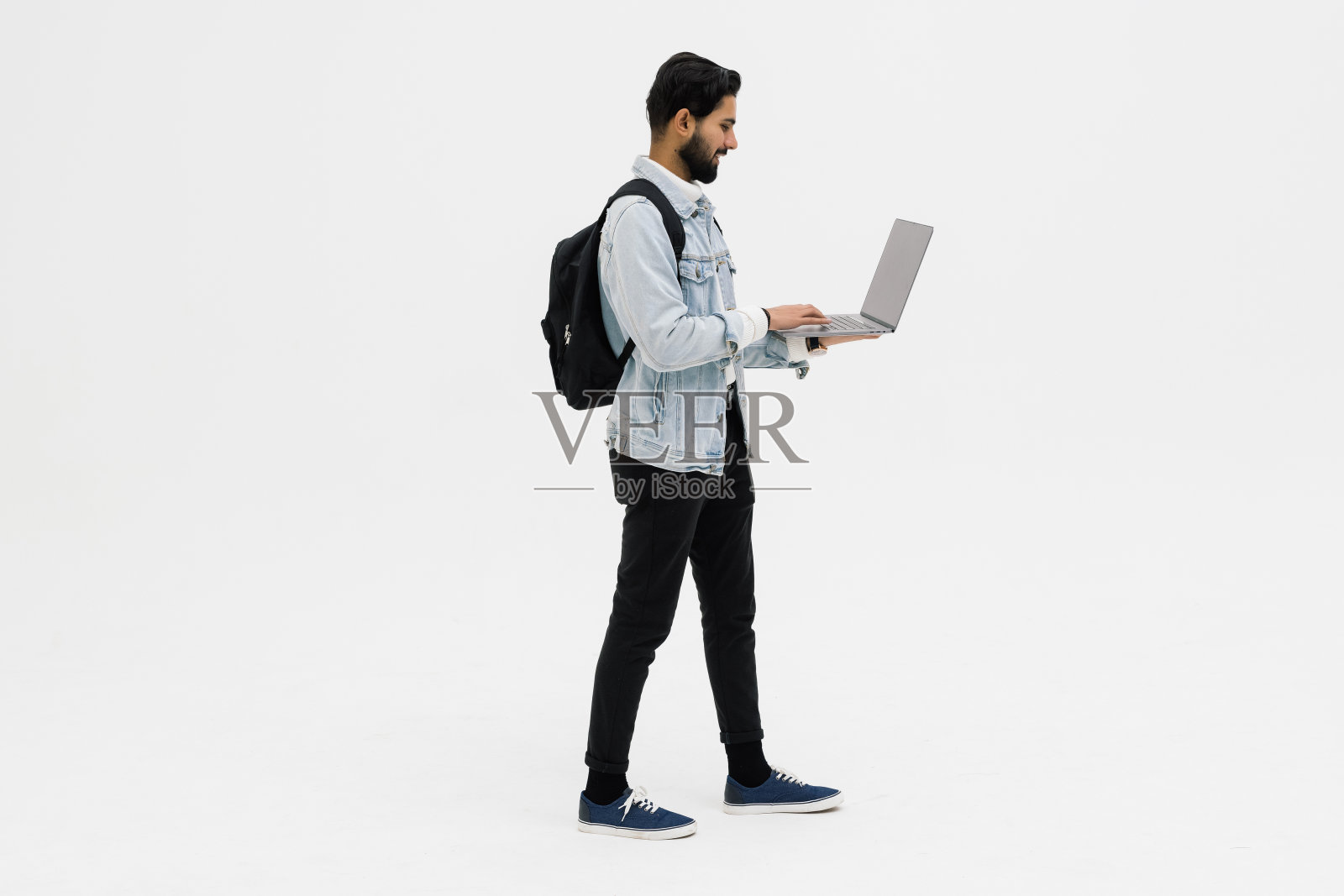 印度英俊的年轻人背着背包站着,用笔记本电脑照片摄影图片