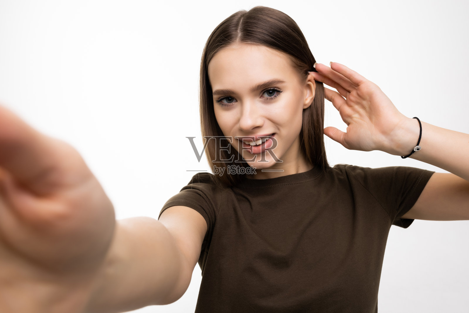 一个微笑的女人在白色背景下用智能手机自拍的照片照片摄影图片