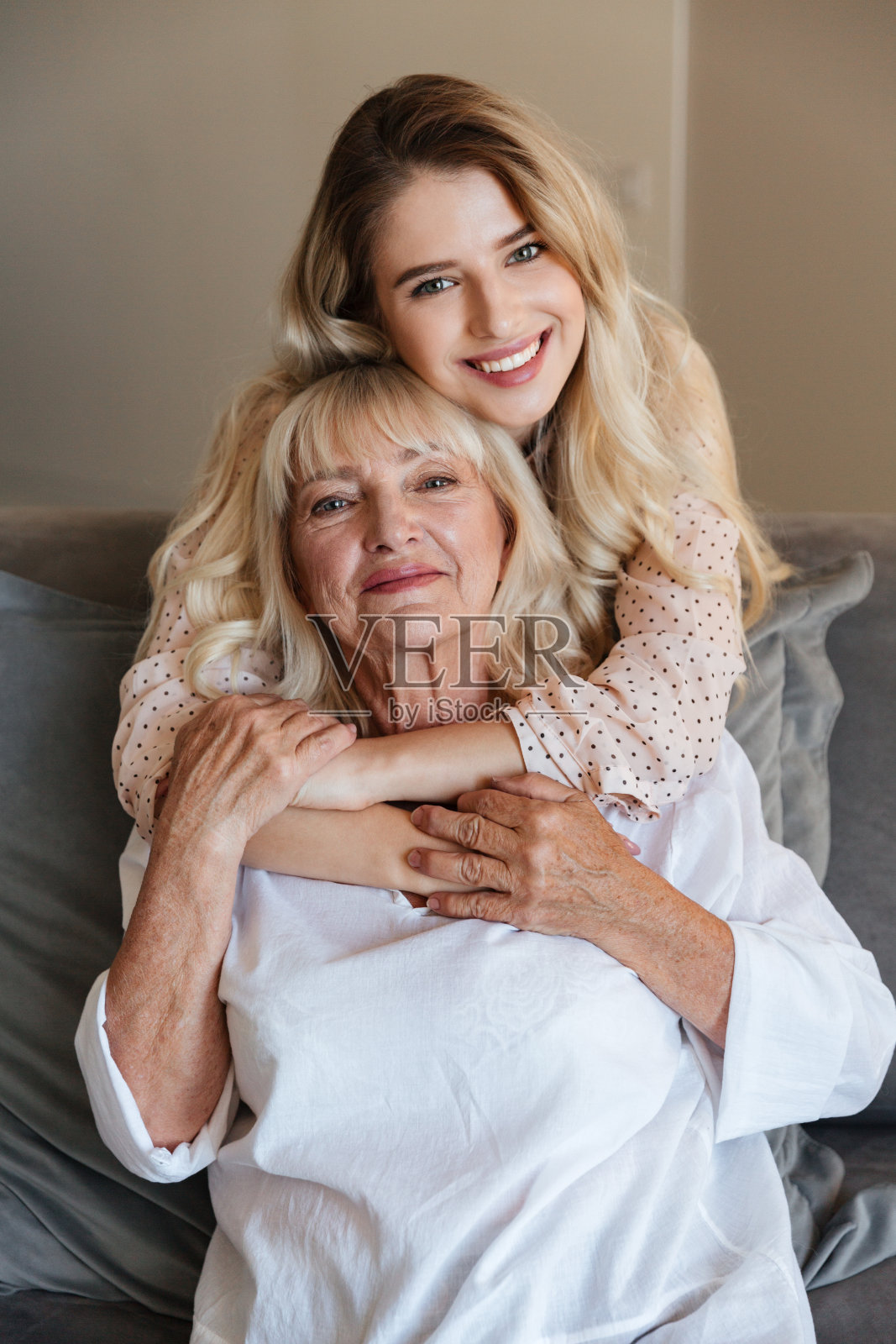 快乐的年轻女士和奶奶坐在家里的沙发上照片摄影图片