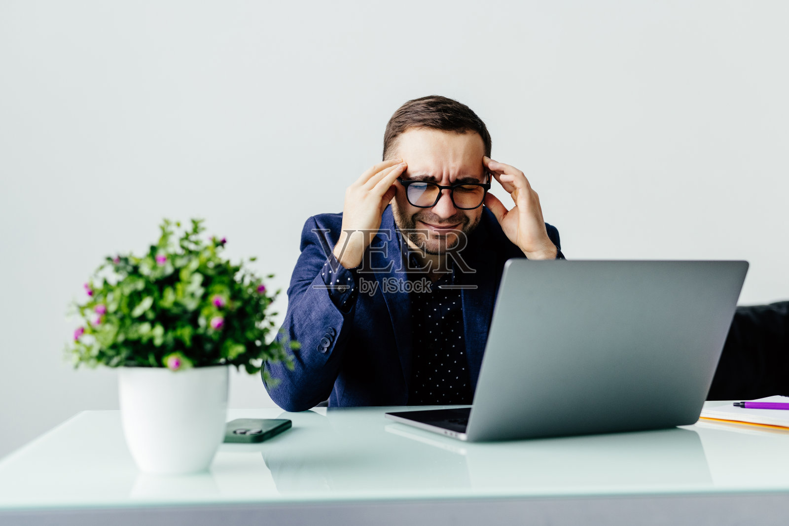 感觉累了。沮丧的年轻英俊男子坐在他的工作地点,看起来筋疲力尽照片摄影图片