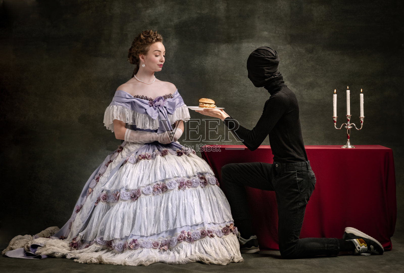 年轻美丽的女子形象在中世纪的皇家人在文艺复兴风格的服装和她的页面孤立在黑暗的复古背景。照片摄影图片