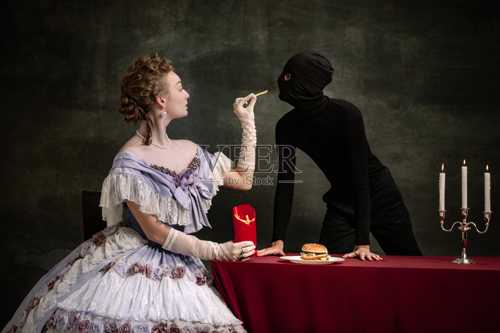 年轻美丽的女子形象在中世纪的皇家人在文艺复兴风格的服装和她的页面孤立在黑暗的复古背景。照片摄影图片