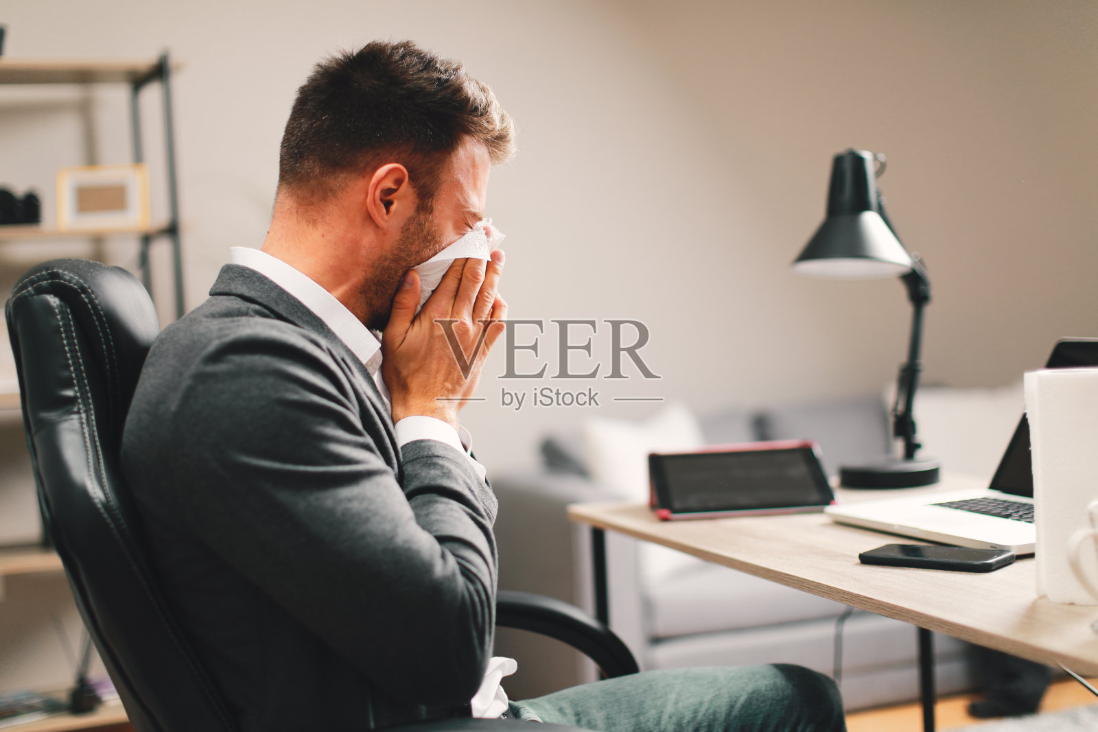 一个年轻人在工作时感冒了,用纸巾擦了擦鼻子照片摄影图片