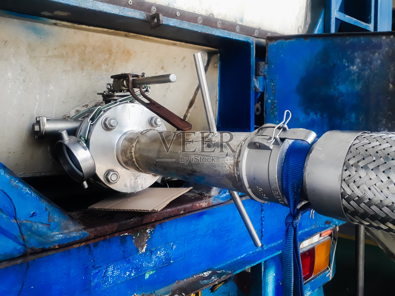 液体物料从油罐到等罐车灌装。装载物料,采用铁软管(软软管)照片摄影图片