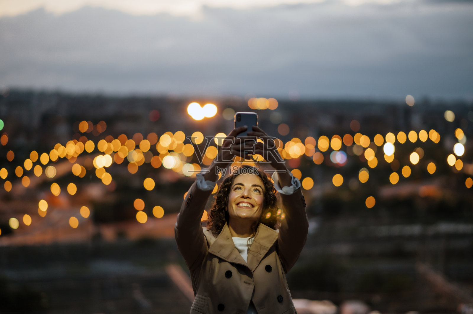 美丽的女人用手机与城市背景散景效果。照片摄影图片