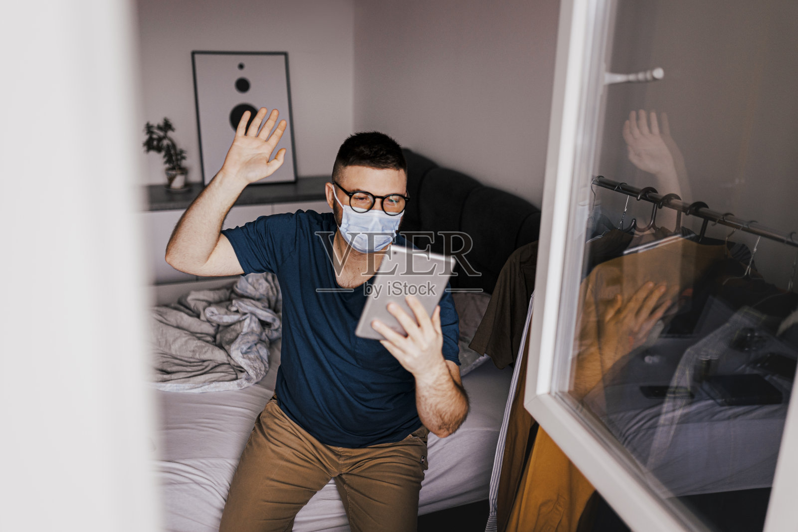 在冠状病毒大流行期间,一名年轻人在隔离期间使用他的数字平板电脑照片摄影图片