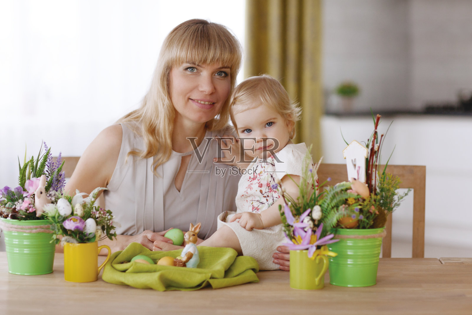 妈妈和孩子们拿着彩色的复活节彩蛋坐在餐桌上照片摄影图片