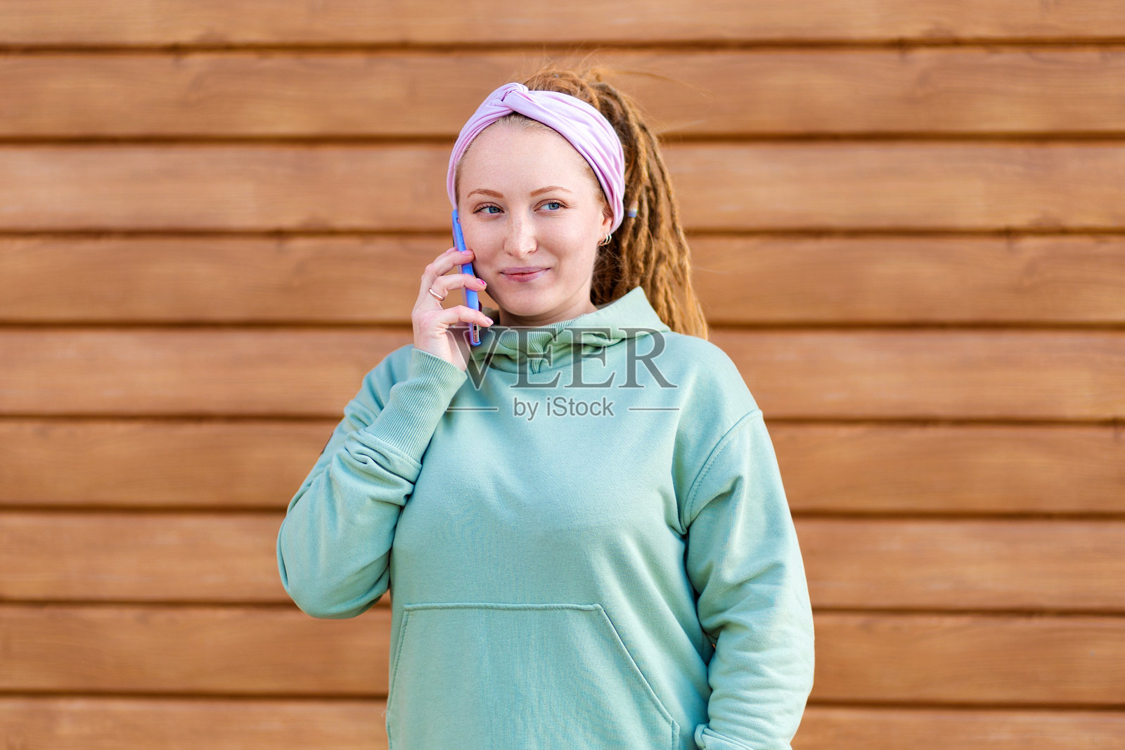一个留着长发绺的漂亮年轻女人打电话来。木条纹背景。副本的空间。沟通的概念照片摄影图片