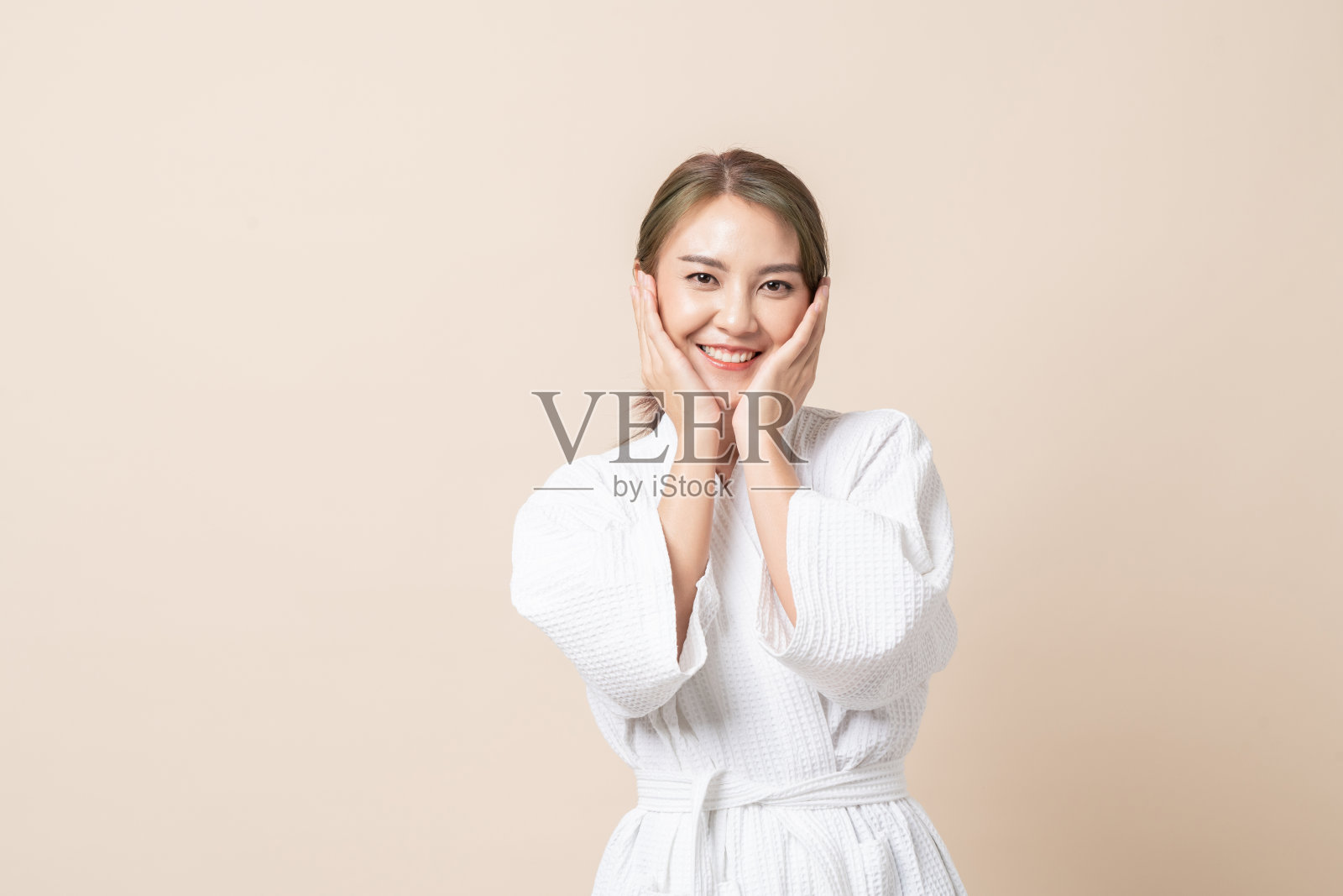 肖像亚洲妇女在浴袍上棕色孤立的工作室背景。照片摄影图片