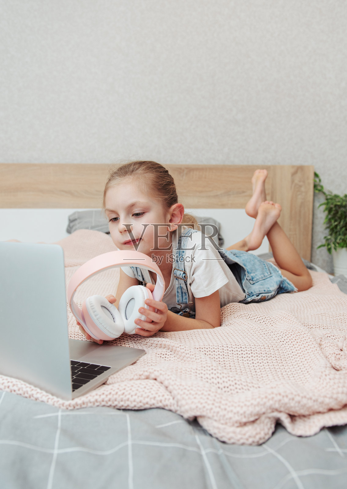 小女孩在卧室用笔记本电脑在线学习。照片摄影图片