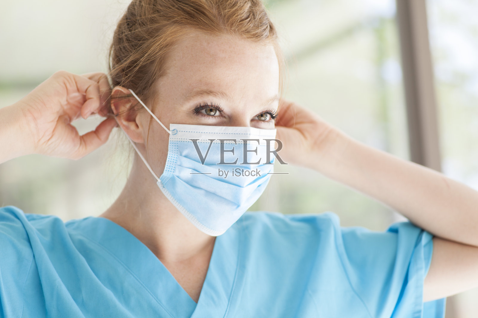 年轻漂亮的红发女护士,穿着医用口罩照片摄影图片